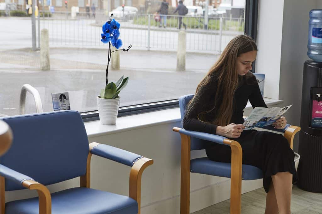 Girl sitting reading leaflet in reception area